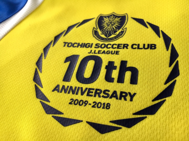 【2018コンフィットTシャツ】
・今シーズンモデルのコンフィットシャツの発売です！
レプリカはちょっと高くて&hellip;　という方々にはこちらのコンフィットシャツがオススメです。
しかも今シーズンは10周年アニバーサリーロゴ入りデザインとなっておりますので記念にもなります。
お子様から大人の方までどうぞ！
背中のバリエーションは5種類です。
■価格
110,130,150センチ ⇒ 4,104円　　※＃8、＃9、＃14は150センチサイズ以上の販売となります。
S，M，L，LLサイズ ⇒ 4,320円
■販売場所：ファンエリア内グッズ売店、ホームゴール裏グッズ売店