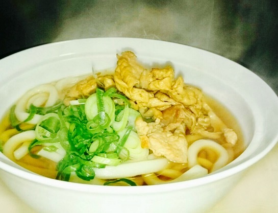 「肉うどん」・あらかじめ下味して火を通した国産豚肉を、お客様に提供する直前にフライパンで炙り味を調え、アツアツの状態で提供致します。■価格：700円 ■販売店舗：NASU no Maki Udon（フードコート）