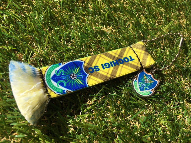 「マフラーキーホルダー」
・どこに付けるかはあなた次第！チェック柄のマフラーキーホルダーです。
■価格：972円
■販売場所：フードコートグッズ売店、ホームゴール裏グッズ売店